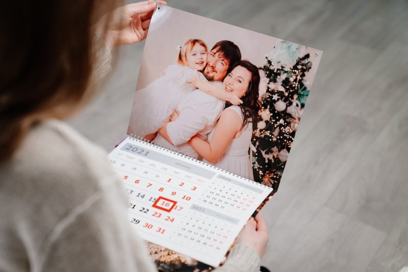 A woman looks at a calendar with a family photo as the main cover image on top.